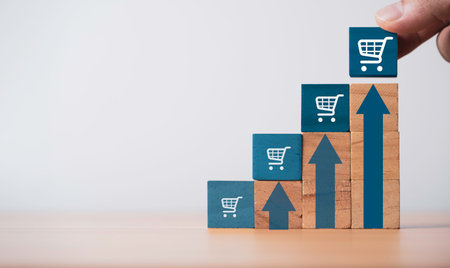 Hand putting shopping cart trolley on the top of up arrow for business sale increasing growth volume concept.の写真素材