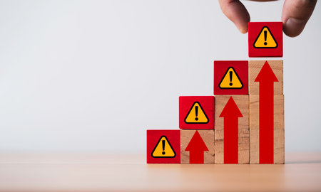 Hand putting exclamation waring and caution sign symbol on red up arrow for high risk and...