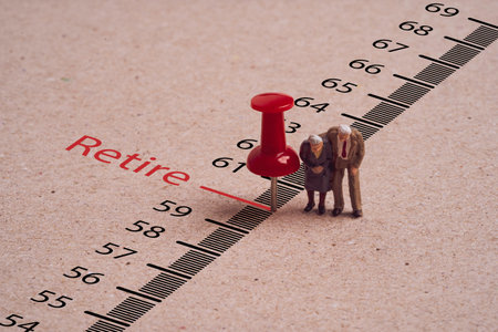 Miniature figure couple Senior Pensioners standing with red pin on and retire wording for time to retirement concept.の写真素材