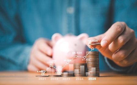 Businessman putting coin on the top of increasing coins stacking with graph and piggy bank for deposit and saving to investment to get profit and benefit concept.の写真素材