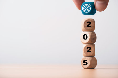 Hand putting blue dartboard with arrow on the top of 2025 year for setup business objective target and goal in new year concept.の写真素材