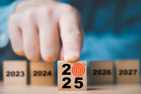 Hand pushing 2025 year with dartboard and arrow among another year for 2025 setup business objective target and goal concept.の写真素材