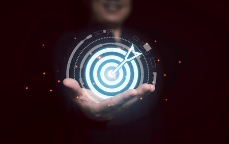 Businessman holding glowing virtual blue dartboard with arrow for Business Achievement objective target concept.の写真素材