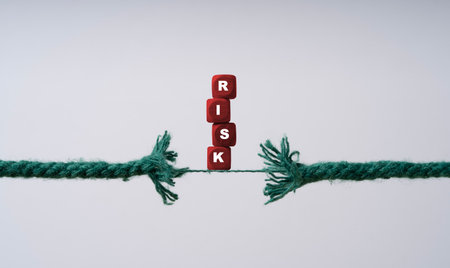 Risk wording on red wooden block cube on the rope is breaking for risk assessment and management concept.の写真素材