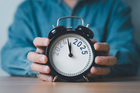 Businessman holding 2024 and 2025 on black alarm clock for preparation of Merry Christmas and Happy new year concept.の写真素材