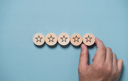 Hand input five stars on wooden block and blue background for the best customer satisfaction and evaluation for good quality product and service.の写真素材