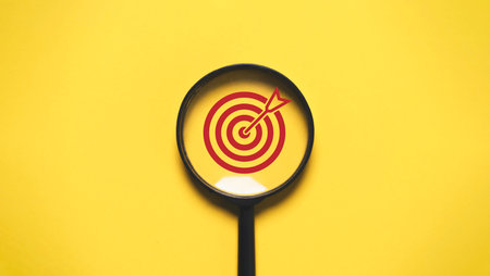 Red Target board inside of magnifier glass for focus business objective on yellow background and copy space.の写真素材