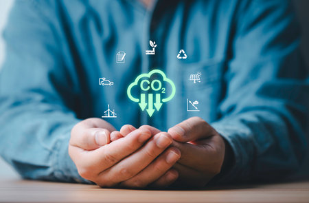 Businessman holding carbon reduction sign with environment icon include green factory recycle electric vehicle for carbon footprint and carbon credit to limit global warming from climate change.の写真素材