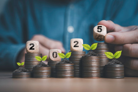 Businessman hand flipping wooden block cube from 2024 to 2025 on coins stacking for business budget planing and investment growth of new year concept.の写真素材