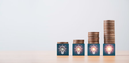 Increasing coins stacking on glowing lightbulb icon for problem solving solution idea and creative can make more money concept.の写真素材