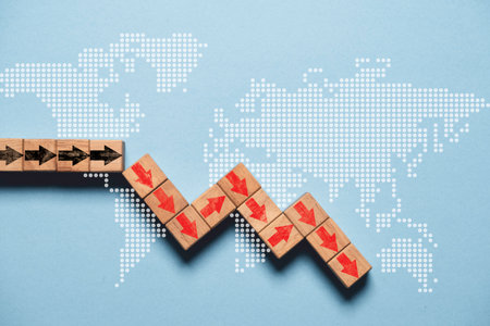 Red down arrow on wooden block cube with world map for global economic crisis depression concept.の写真素材