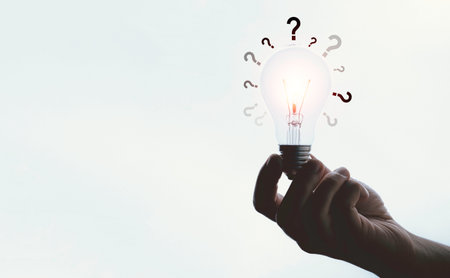Hand holding glowing lightbulb with question mark and copy space for creative thinking and problem solving solution concept.の写真素材