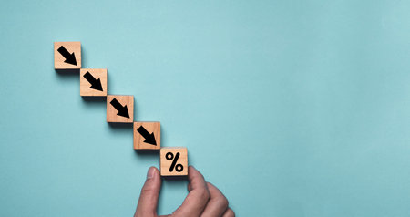 Hand holding percentage with down arrow on blue background and copy space for decreasing of business investment debt interest and economic recession concept.の写真素材