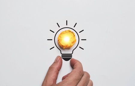 Yellow scrap paper inside of lightbulb drawing which it glowing on hand for creative thinking idea problem solving solution and innovation concept.の写真素材