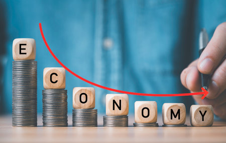 Businessman writing down arrow with Economy wording  on decreasing coins stacking for global economic recession crisis concept.の写真素材