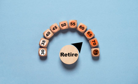 Wooden blocks arranged in a semicircle with numbers representing different ages, centered around a block labeled "Retire." It suggests the concept of retirement and age concept.の写真素材