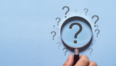 Hand holding magnifier glass with question mark for focus and concentrate in problem solving and solution concept.の写真素材