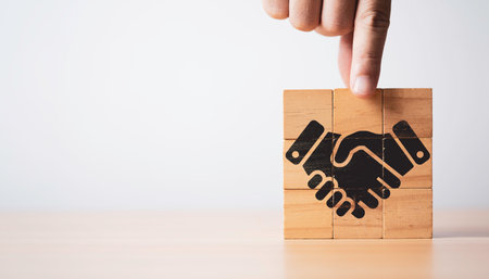 Hand assemble wooden block cube which print screen black business handshake icon for partnership deal agreement and collaboration concept.の写真素材