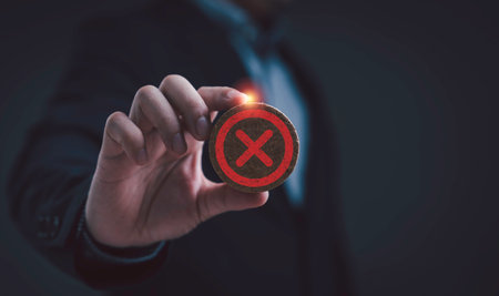 Businessman holding wooden round badge with red cross mark symbol, representing rejection decline disapproval failed process wrong decision mistake cancellation or negative response.の写真素材