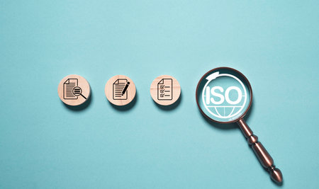 Magnifying glass focusing on symbol with wooden blocks showing document checklist and audit process concept of quality control certification standard assurance and business management systemの写真素材