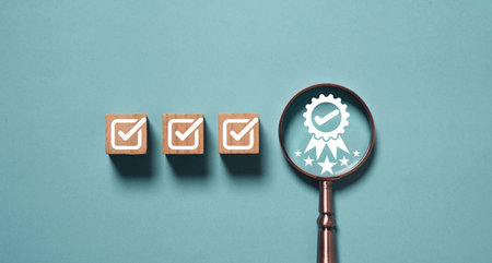 Wooden blocks with check marks and magnifying glass showing quality assurance badge symbol representing product certification standard control and business excellence conceptの写真素材