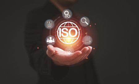 Businessman holding glowing ISO icon representing quality management system certification international standard assurance and continuous improvement for business excellence.の写真素材