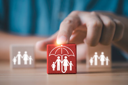 A concept image of a hand choosing a wooden block with a family protection umbrella symbol representing insurance safety security care support and risk management for family and life planning contentの写真素材