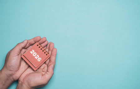 Hands holding a 2026 calendar representing preparation for the new year future planning goal setting vision and personal development for business strategy and life planning themesの写真素材