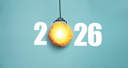 A glowing paper light bulb placed between the numbers 2026 represents a creative idea concept symbolizing innovation new goals inspiration planning and fresh possibilities for the upcoming year.の写真素材