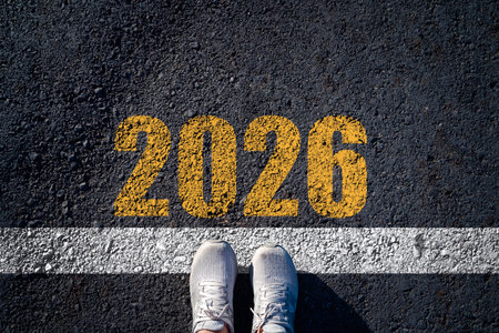 A top down view of shoes standing at a white starting line with the bold number 2026 painted on...