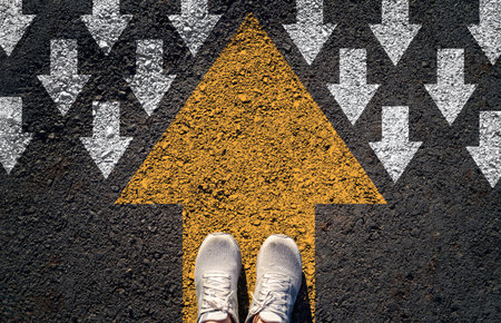 Top view of shoes standing on a bold yellow arrow pointing forward against a field of white arrows...