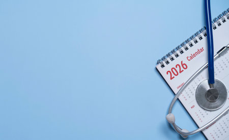 Desk calendar with medical stethoscope on blue background and copy space for healthcare planning or...