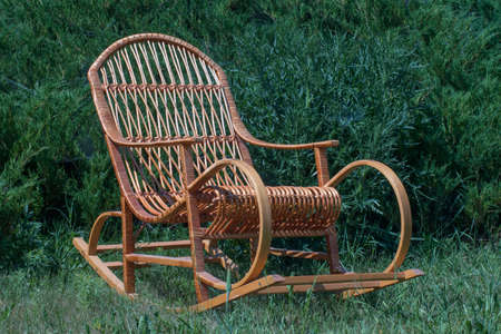 rocking chair on a green lawn, against the background of juniperの写真素材