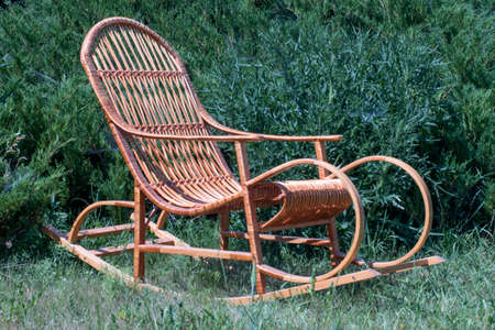 rocking chair on a green lawn, against the background of juniperの写真素材