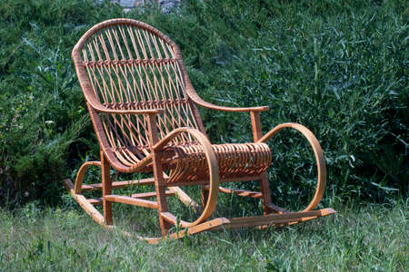 rocking chair on a green lawn, against the background of juniperの写真素材