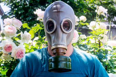 man in a gas mask on a background of rosesの写真素材
