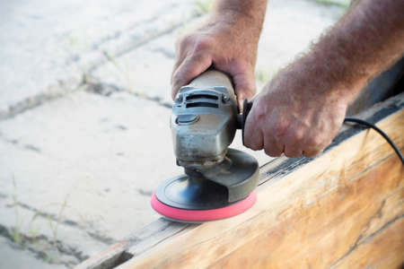 man polishing a board with a manual angle grinder, close-upの写真素材