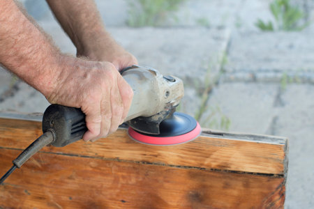 man polishing a board with a manual grinder, close-upの写真素材