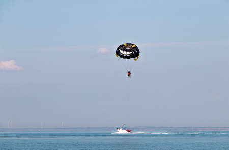 tourists hover above the water with a parachute tied to a boatの写真素材