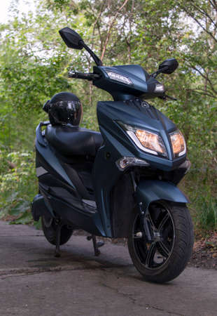 electric motorcycle with a helmet on the seat, stands on a forest roadの写真素材