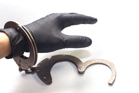 handcuffed on a hand with a black glove, on an isolated backgroundの写真素材