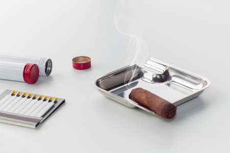 Ashtray with a smoldering cigar and an open box of matches, on an isolated white backgroundの写真素材