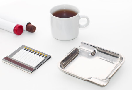 Ashtray with a smoldering cigar a cup of coffee and an open box of matches, on an isolated white backgroundの写真素材