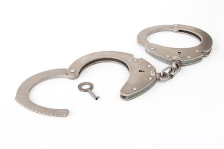 handcuffs with a key in the form of a heart, on a white isolated backgroundの写真素材