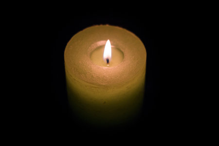 Candle burning in darkness, color yellowの写真素材