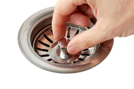 Human hand adjusts kitchen waste sewer filter, close-up, on isolated white backgroundの写真素材