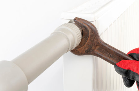 technician tightening central heating radiator fitting, close-up on isolated whiteの写真素材