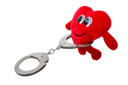 heart in handcuffs, a fun soft toy in handcuffs, on an isolated white backgroundの写真素材