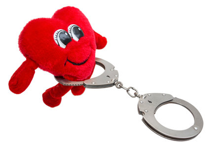heart in handcuffs, a fun soft toy in handcuffs, on an isolated white backgroundの写真素材