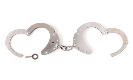 handcuffs with a key in the form of a heart, on a white isolated backgroundの写真素材